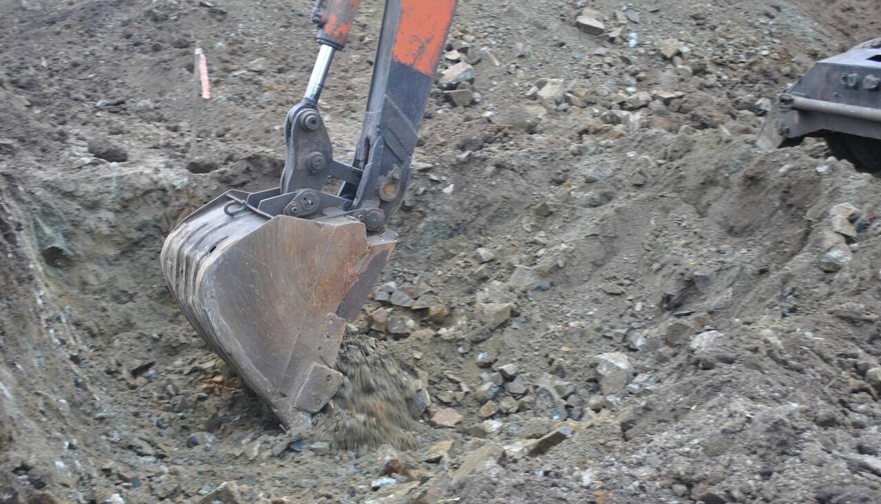 Excavator bucket digging into rocky soil